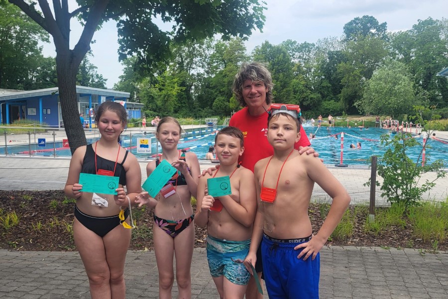 Drei Kinder halten ihr Schwimmabzeichen in den Händen.