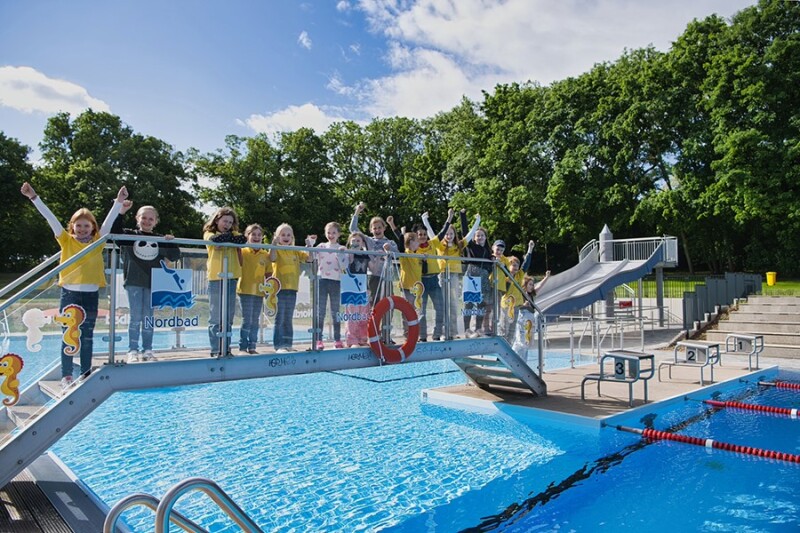Kinder stehe freudig auf einer Brücke des Freibad Nordbad Halle.