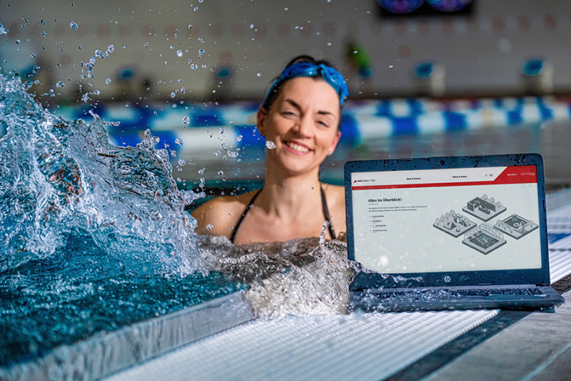 Frau im Wasser, Laptop steht am Beckenrand