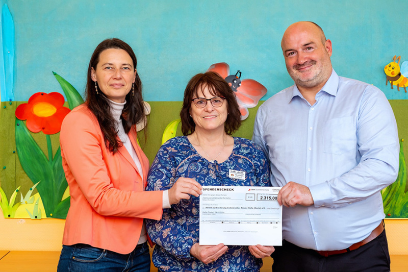 Mitarbeiter übergeben einen Scheck.