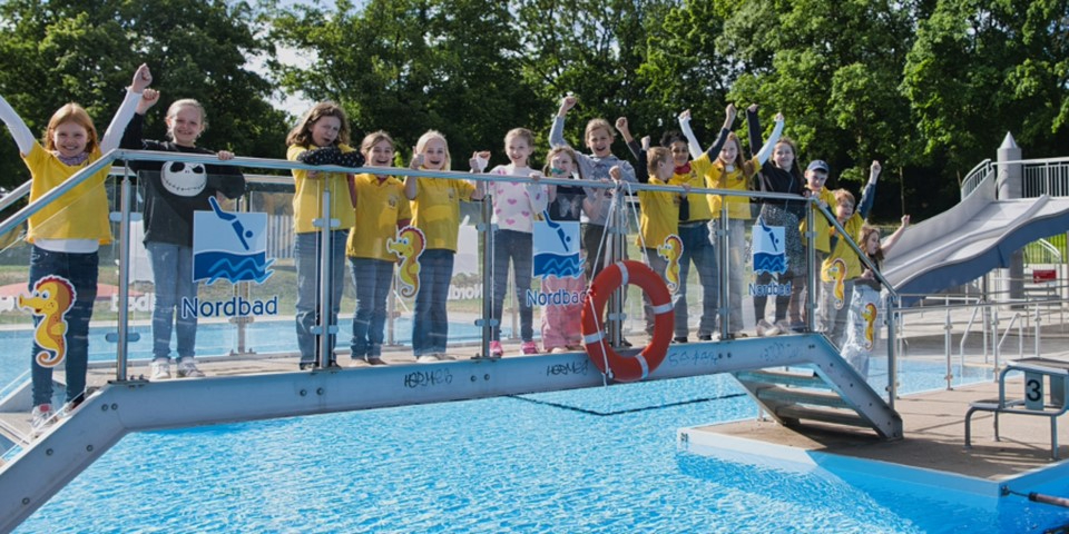 Kinder stehen freudig auf einer Brücke des Freibad Nordbad Halle.