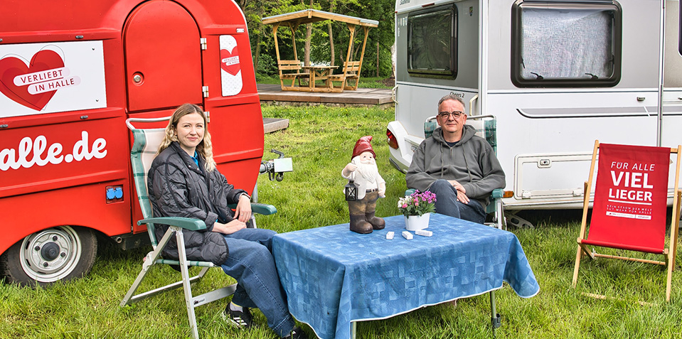 Campingplatzbesucher sitzen vor zwei Wohnwagen auf dem Campingplatz am Nordbad