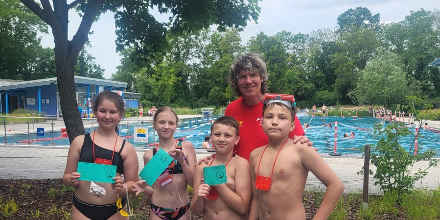 Drei Kinder halten ihr Schwimmabzeichen in den Händen.