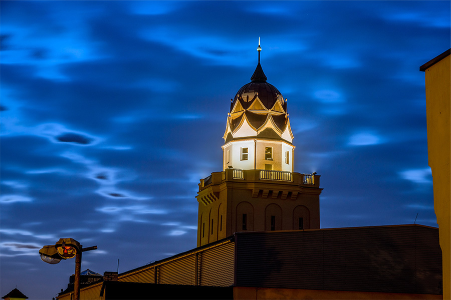 Der Turm des Stadtbades wird angestrahlt. Das Bild wurde aus der Froschperspektive aufgenommen. Der Himmel ist dunkelblau.