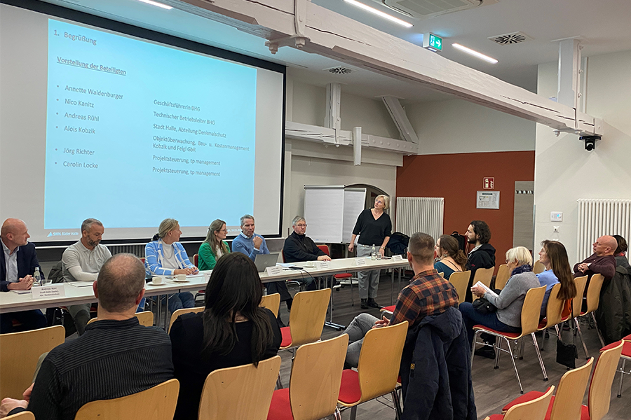 Menschengruppe sitzt vor einer Präsentation.