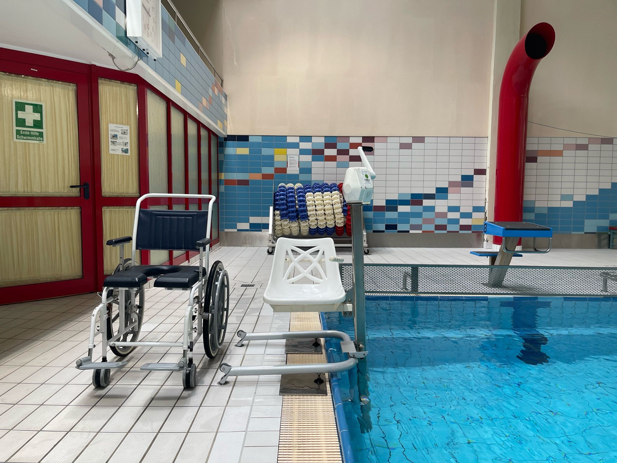 Ein Rollstuhl steht neben dem Poollift am Beckenrand des Schwimmerbeckens.