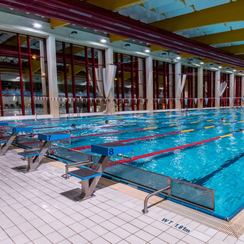 Ansicht eines Schwimmbeckens mit Startblöcken und Schwimmern in Bahnen