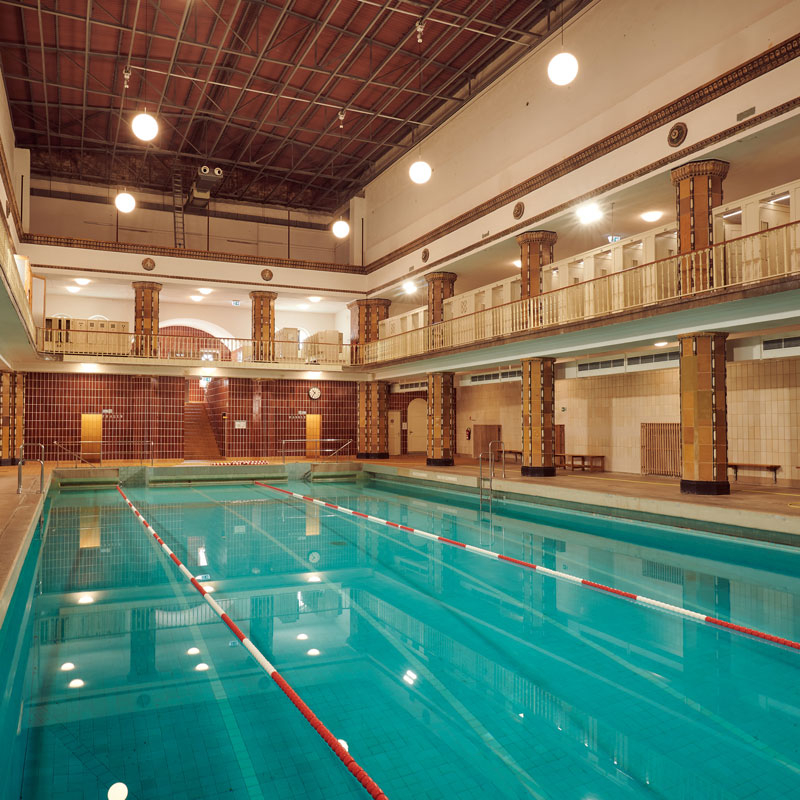 Ansicht des historischen Hallenbads mit Schwimmbecken, Säulen und Galerie